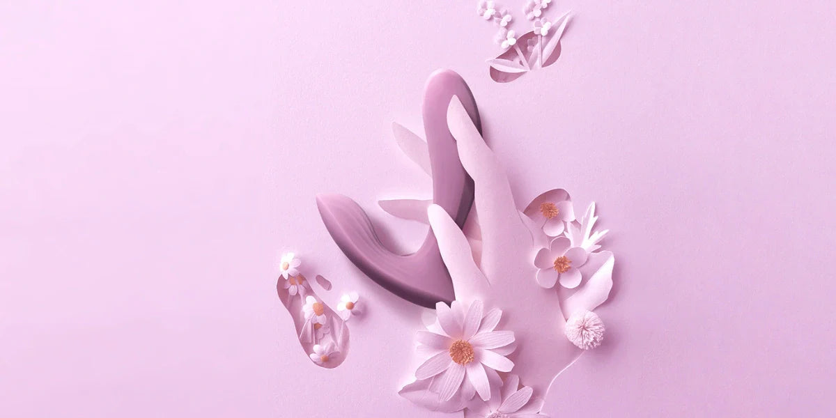 Rosa bild med en hand som håller i en Svakom Erica med blommor omkring