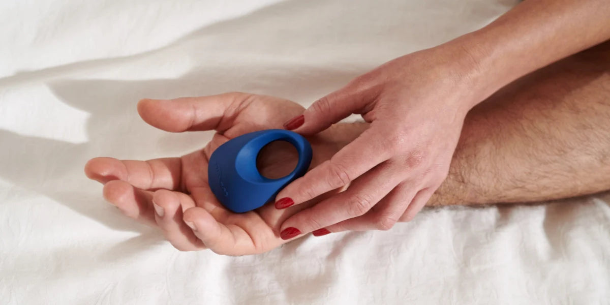 Två händer håller i en We-vibe Pivot penisring