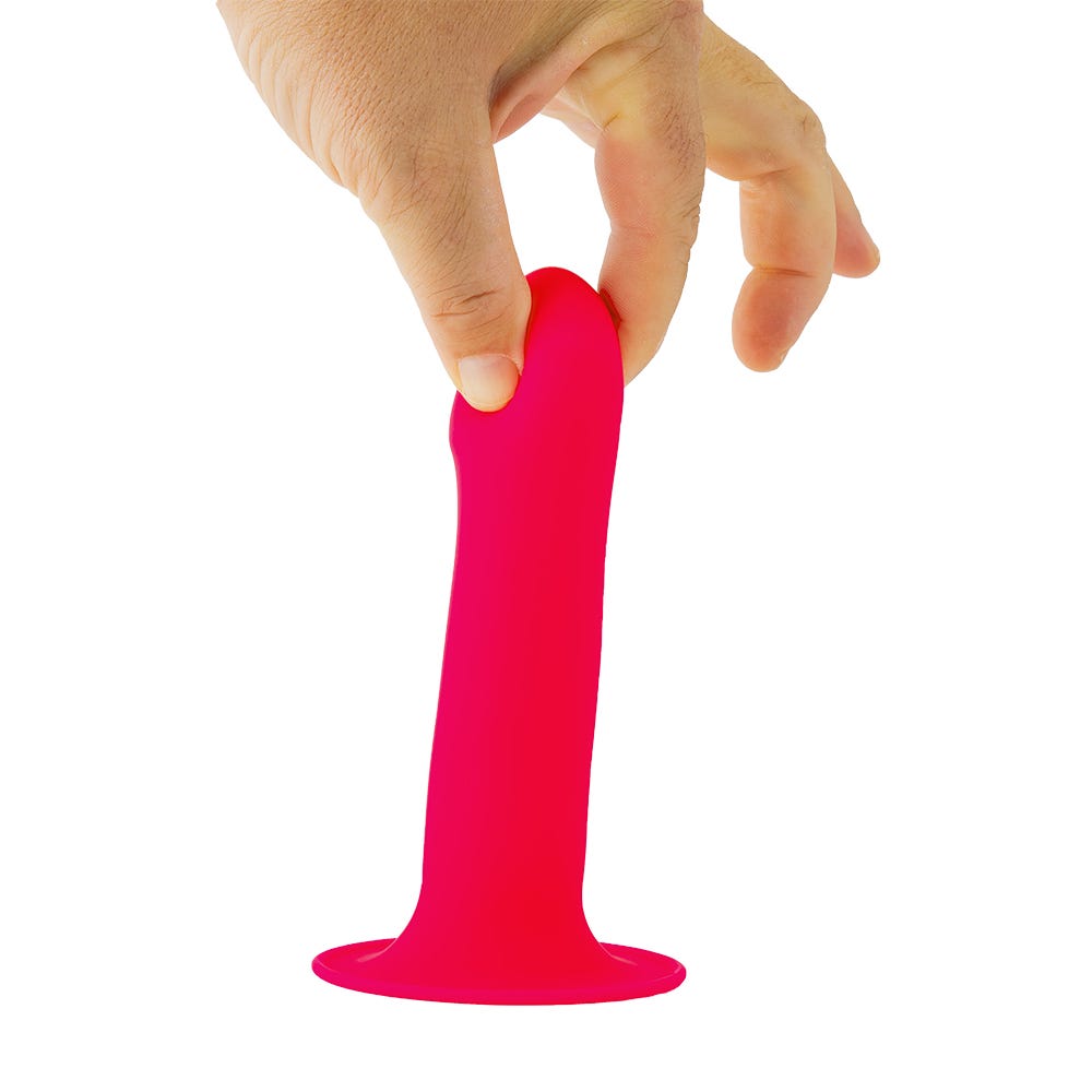 Hand som håller i Solid Love Dildo Pink mot vit bakgrund.