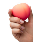 En hand håller i en Romp Peach Clitoral Stimulator