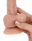 En hand klämmer på ena bollen på Real Fantasy Declan Realistic Dildo with Sliding Foreskin 18 cm
