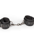 Easytoys Black Leather Handcuffs mot vit bakgrund