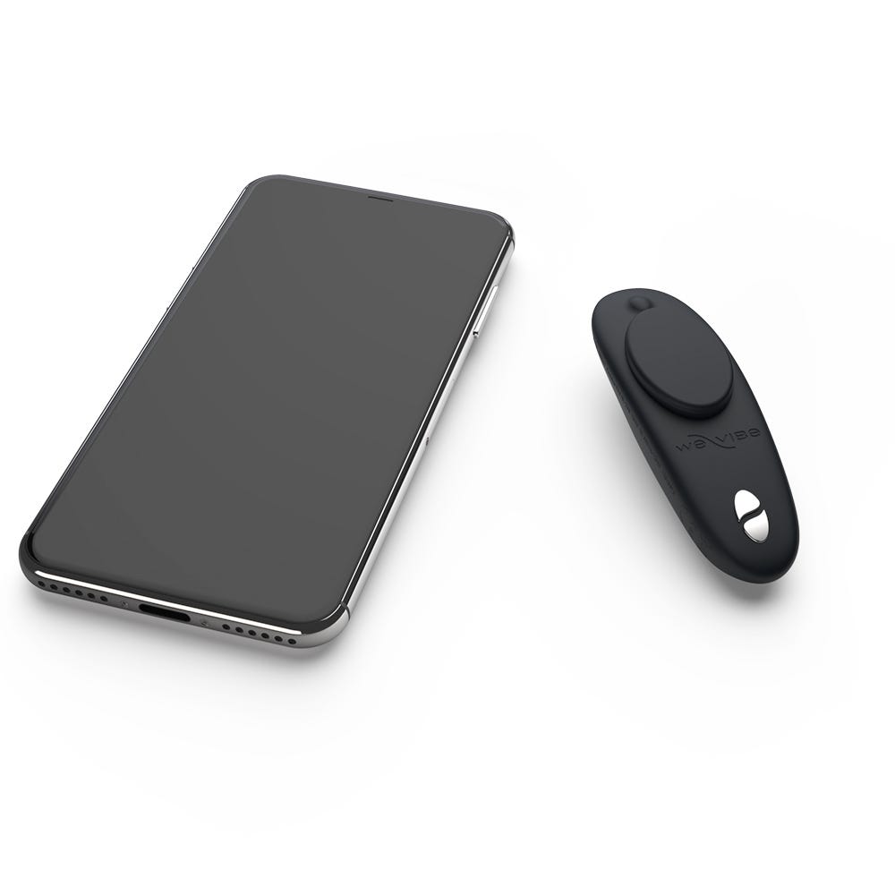 We-Vibe Moxie Satin Black Trosvibrator och smartphone mot vit bakgrund.