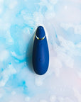 Vattentät lufttrycksvibrator Womanizer Premium 2 Blueberry i vatten med blå bakgrund och skum