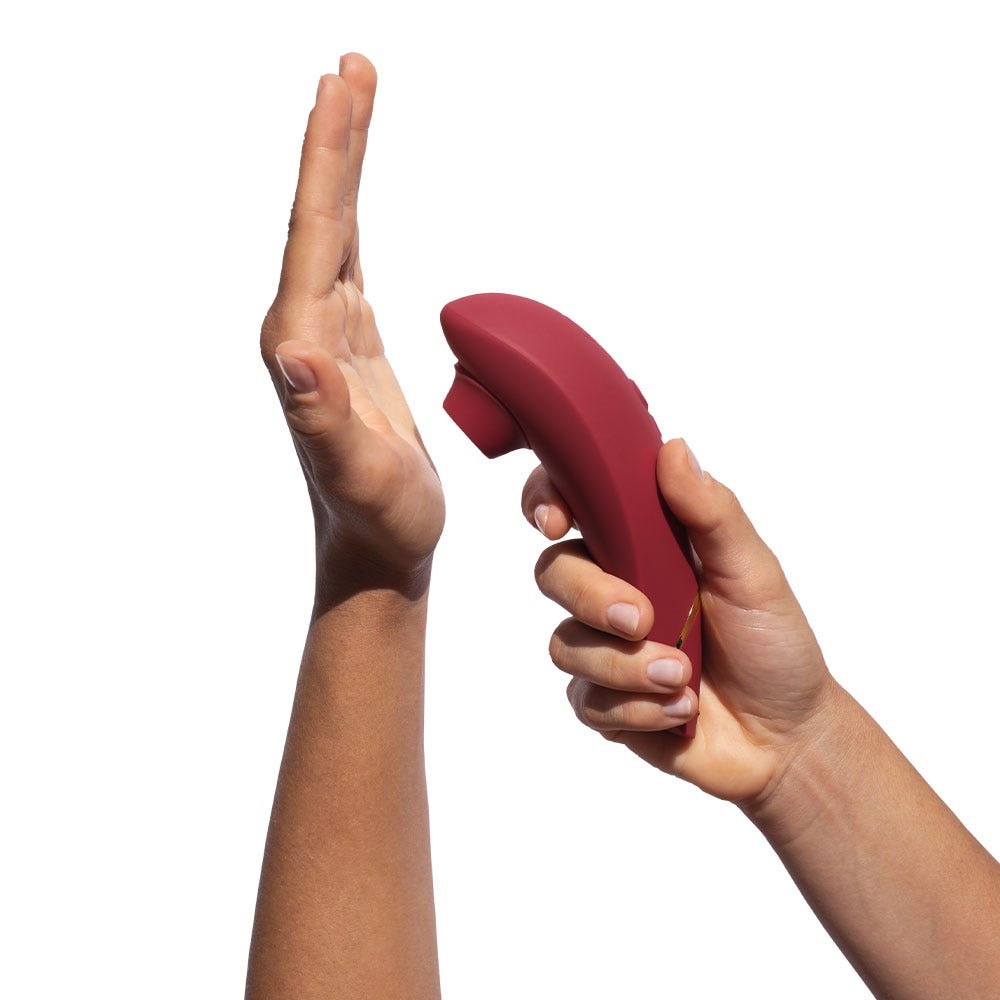 Två händer som håller röd lufttrycksvibrator Womanizer Premium 2 Bordeaux