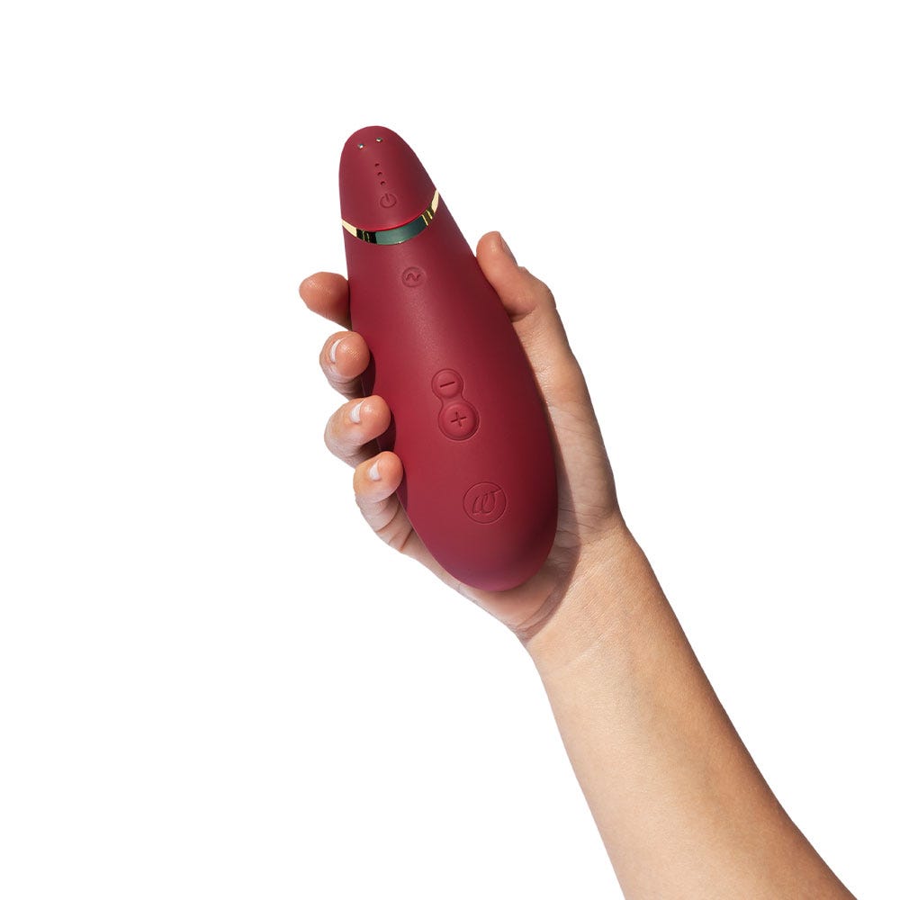 Visar storleken av Womanizer Premium 2 Bordeaux i en hand. Röd färg på en lufttrycksvibrator.