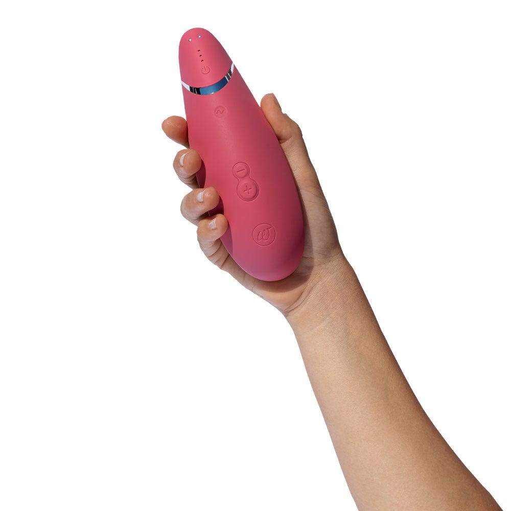 Storlek på Womanizer Premium 2 Raspberry i en hand. Visar upp knapparna och storlek på lufttrycksvibrator