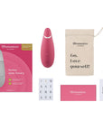 Womanizer Premium 2 Raspberry lufttrycksvibrator med tillbehör. Laddare, munsstycke och en påse som det står "Go. Love Yourself!"