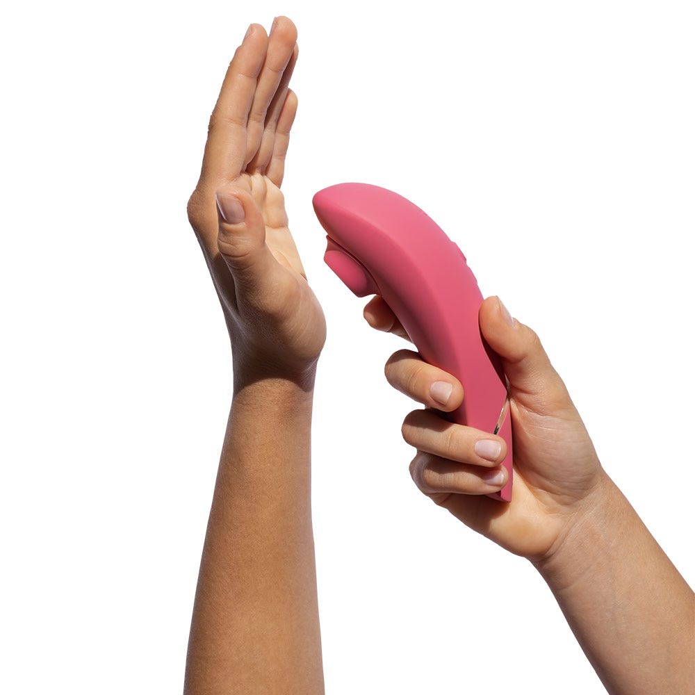 Två händer som håller Womanizer Premium 2 Raspberry. Storleken på lufttrycksvibratorn demonstreras.