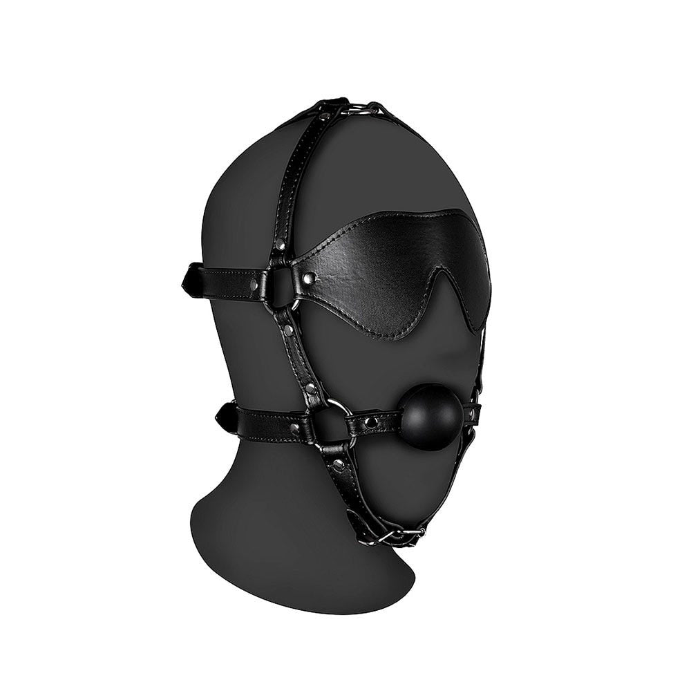 Blindfolded Head Harness with Solid Ball Gag på svart plasthuvud mot vit bakgrund.