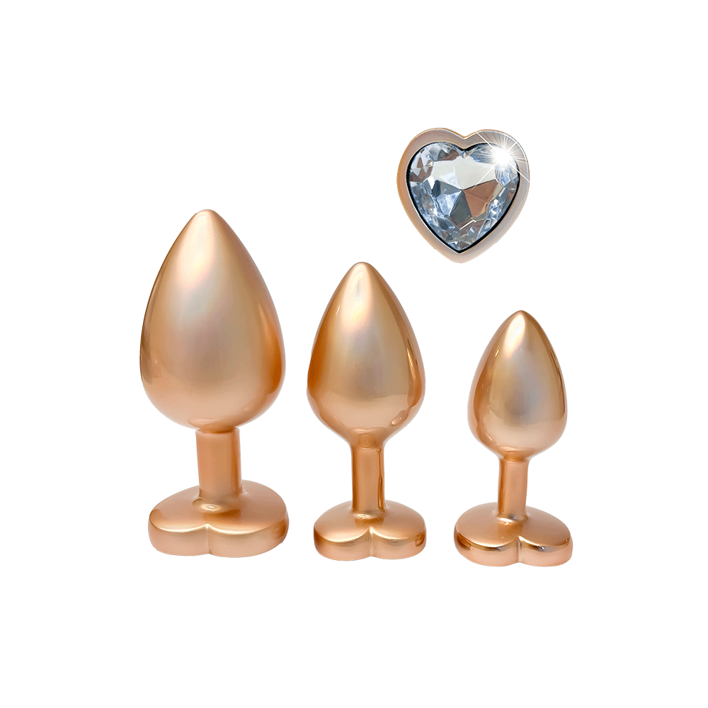 DreamToys Gleaming Love Gold Buttplug Set och ädelsten mot vit bakgrund.