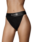 Kvinnlig modell som har på sig Ouch! Vibrating Strap-on Panty Harness with Open Back ståendes mot vit bakgrund. Framsida.