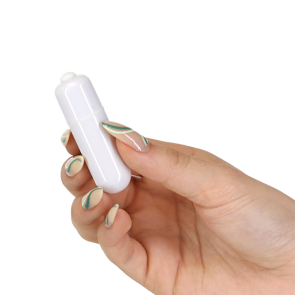 Hand som håller i Pillow Talk Rosy Luxurious Glass Anal Plug with Bonus Bullet bulletvibrator mot vit bakgrund.