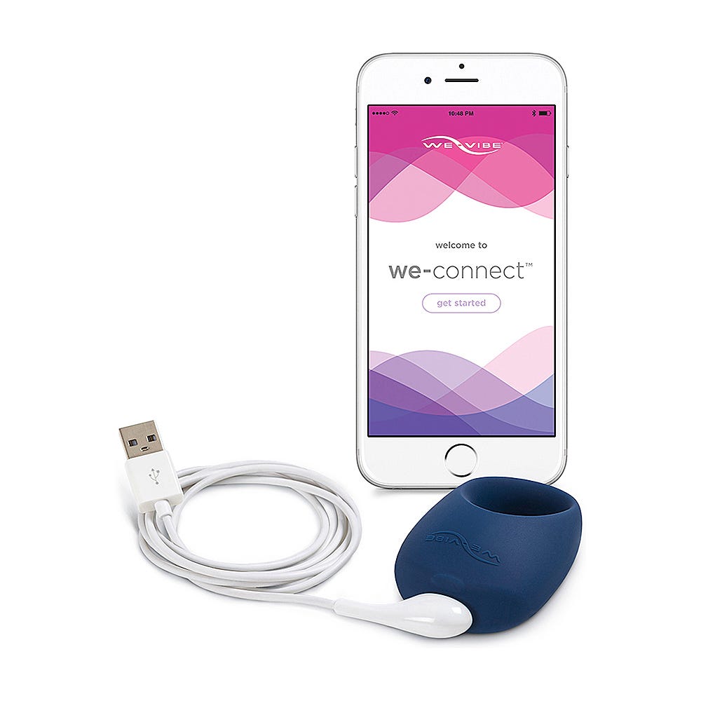 We-Vibe Pivot Vibrerande Penisring, smartphone och USB-laddare mot vit bakgrund.