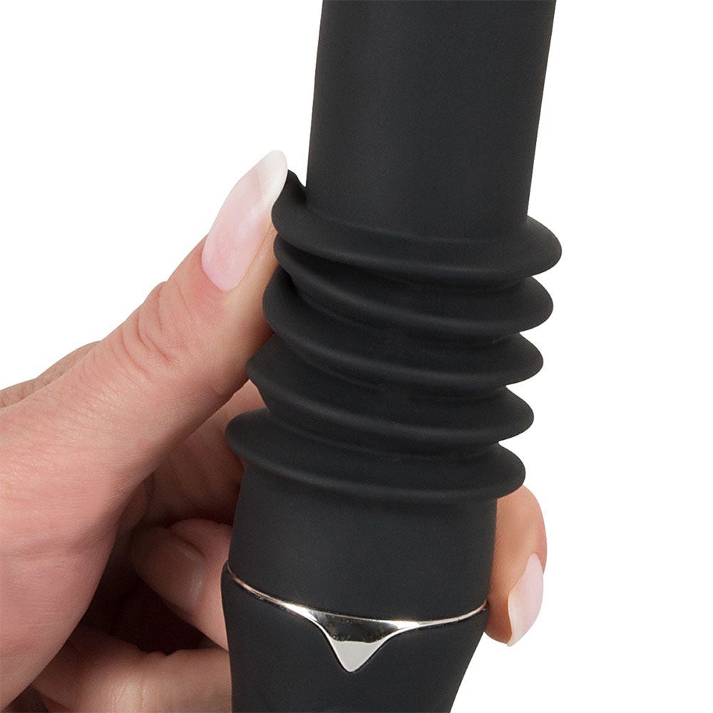 Närbild på Portable Fucking Machine Thrusting Vibrator mellan fingrar med långa naglar.