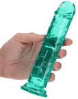 En hand med ljus hud och kortklippta naglar som håller RealRock Dildo with Suction Cup Green 18cm. Vit bakgrund.