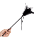 Hand som håller i Secret Play Feather Tickler Black mot vit bakgrund.