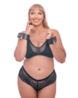 Kvinnlig plus size modell med Sex & Mischief Brat Locking Cuffs runt sina handleder mot vit bakgrund.