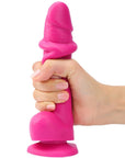 Hand som håller i Strap-On-Me Sliding Skin Realistic Dildo Fuchsia L mot vit bakgrund.