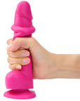 Hand som håller i Strap-On-Me Sliding Skin Realistic Dildo Fuchsia M mot vit bakgrund.