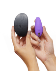 Händer som håller Sync Go Light Purple vibrator och resefodral mot vit bakgrund.