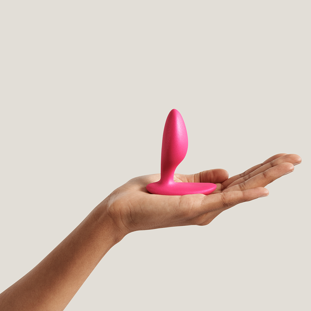 We-vibe Ditto+ Cosmic Pink på en handflata mot beige bakgrund.