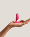 We-vibe Ditto+ Cosmic Pink på en handflata mot beige bakgrund.