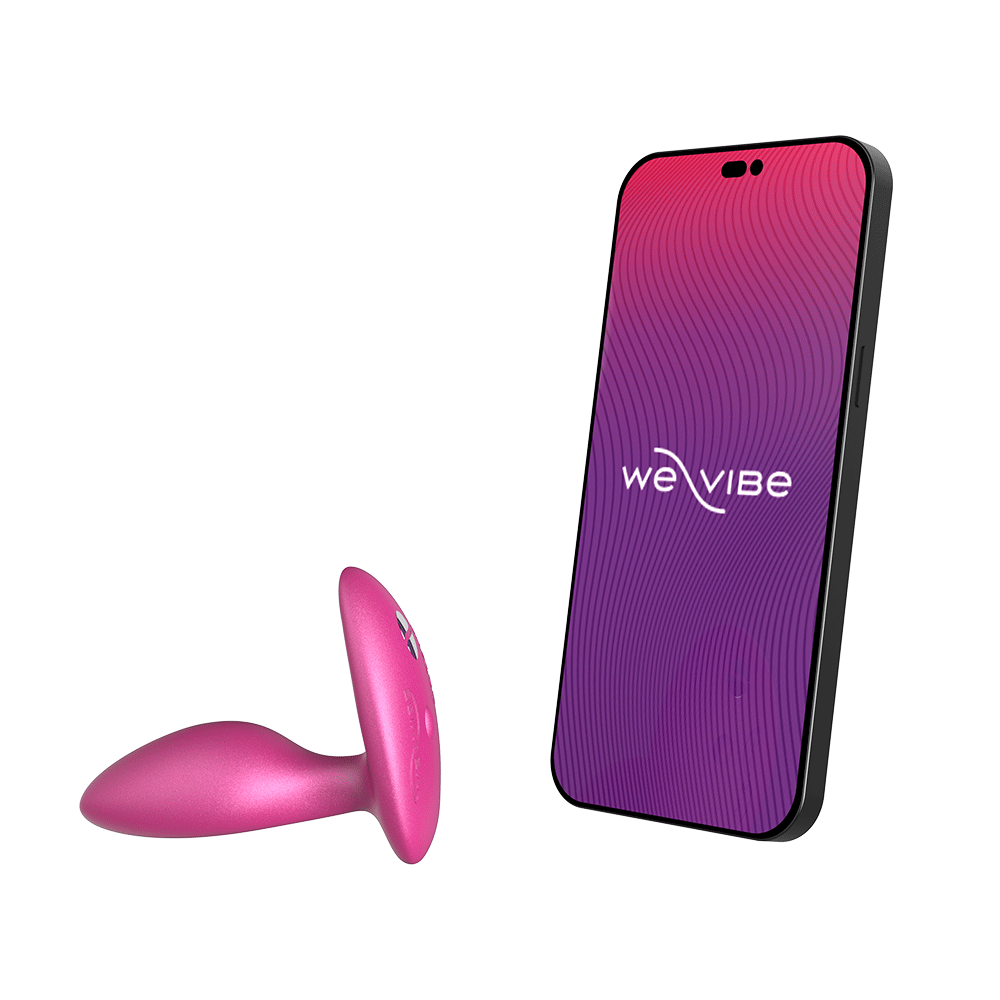 We-vibe Ditto+ Cosmic Pink bredvid en smartphone mot vit bakgrund.