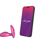 We-vibe Ditto+ Cosmic Pink bredvid en smartphone mot vit bakgrund.