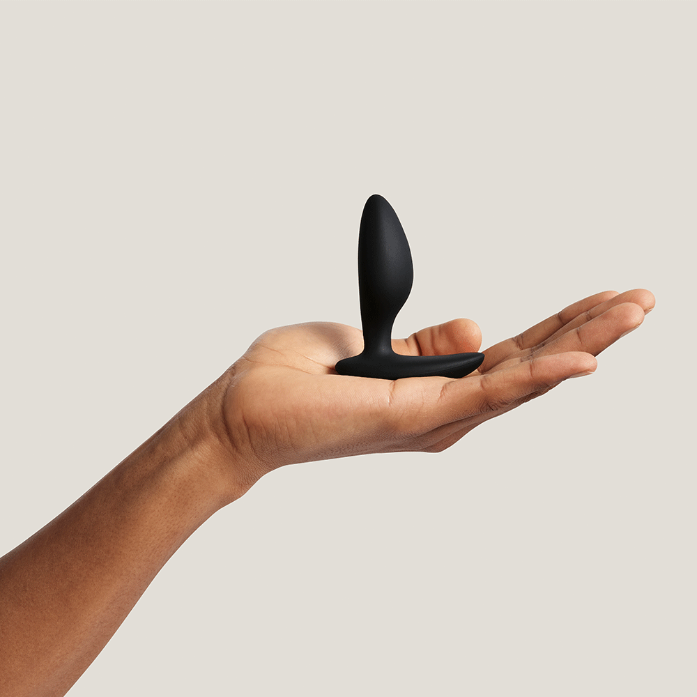 Hand som håller i We-Vibe Ditto+ Satin Black mot beige bakgrund.