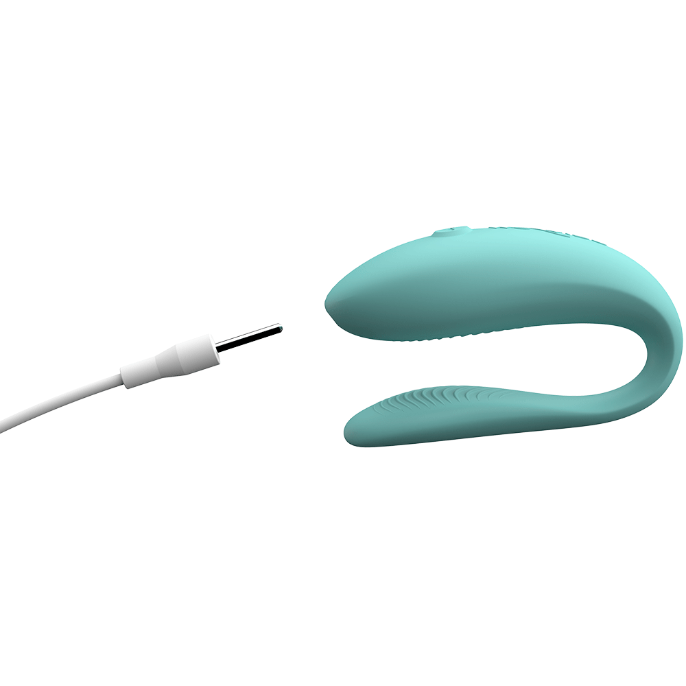 We-vibe Lite Aqua i sidvy med USB-laddare som pekar mot produkten. Vit bakgrund.