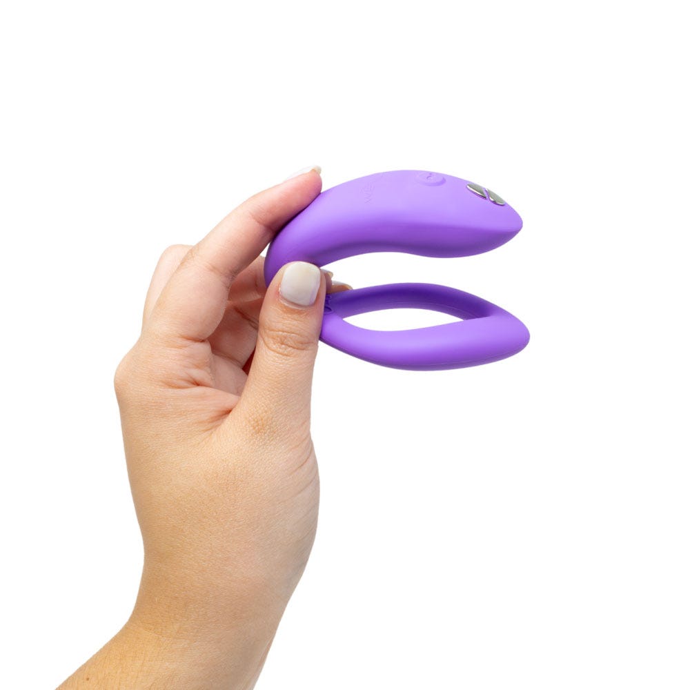 Kvinnlig hand som håller i We-vibe Sync O Light Purple mot vit bakgrund.