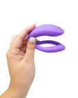 Kvinnlig hand som håller i We-vibe Sync O Light Purple mot vit bakgrund.