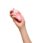 Kvinnlig hand som håller i Womanizer Liberty 2 Vibrant Rose mot vit bakgrund.