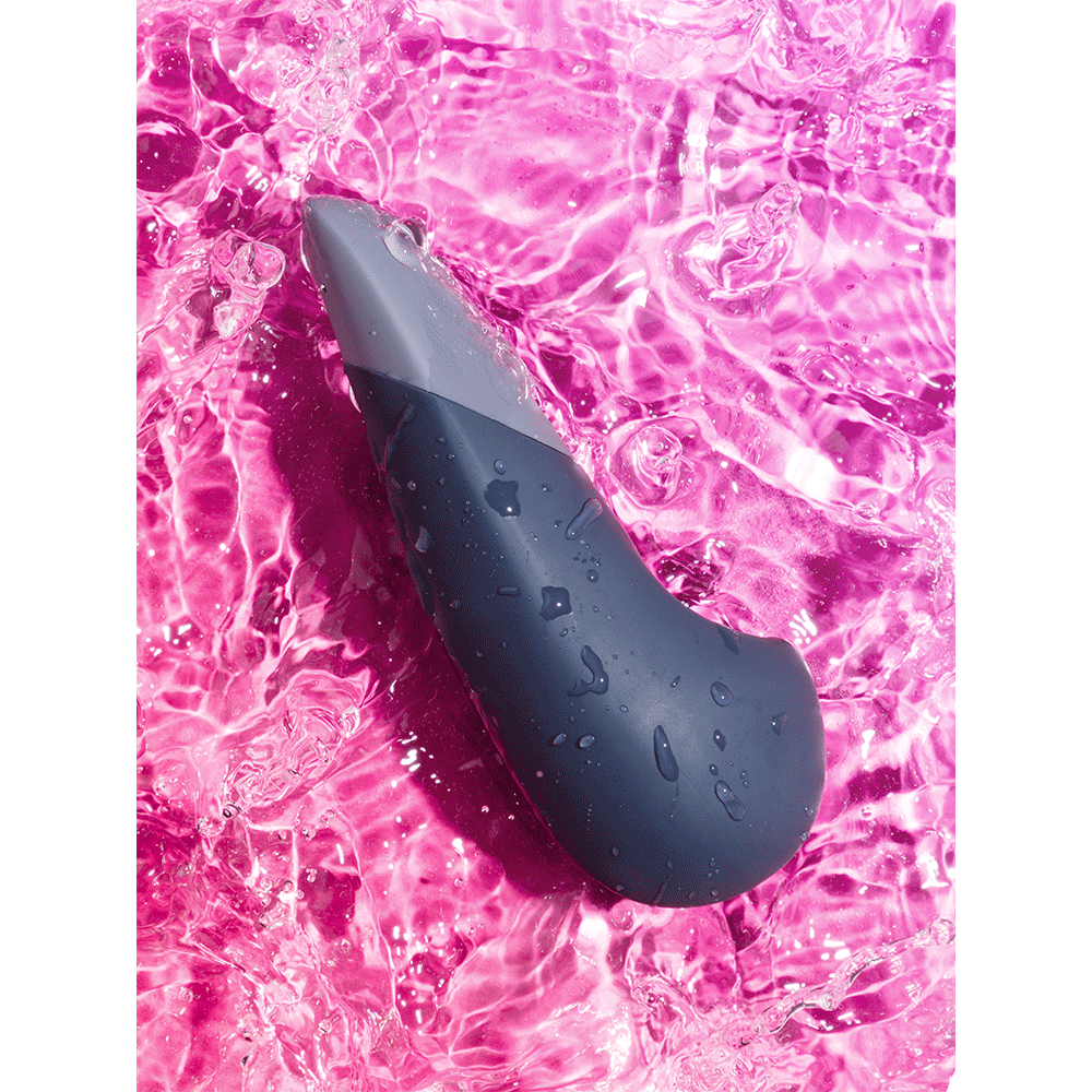 Stämningsbild på Womanizer Vibe Dark Blue Klitorisvibrator i rosa vatten.