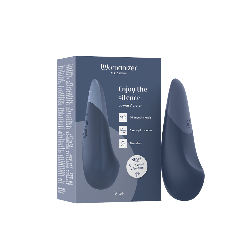 Womanizer Vibe Dark Blue Klitorisvibrator bredvid förpackning.