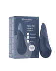 Womanizer Vibe Dark Blue Klitorisvibrator bredvid förpackning.