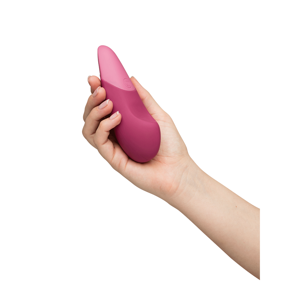 Hand som håller i Womanizer Vibe Dusky Pink Klitorisvibrator.