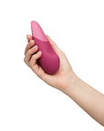 Hand som håller i Womanizer Vibe Dusky Pink Klitorisvibrator.