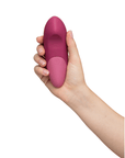 Hand som håller i Womanizer Vibe Dusky Pink Klitorisvibrator så att undersidan syns.